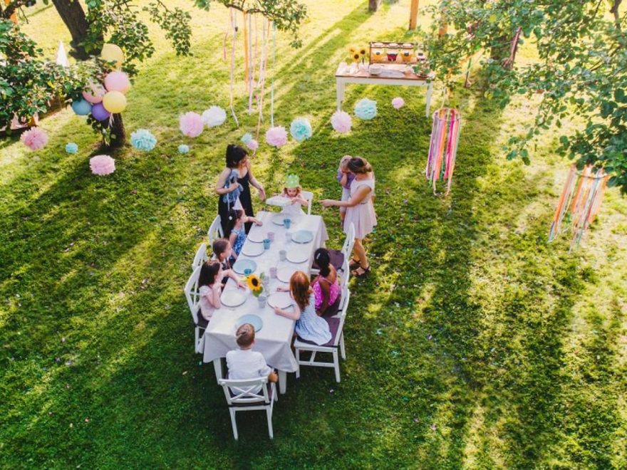 Aerial view of a kids' birthday party with rented tables, chairs and decor set up in a garden