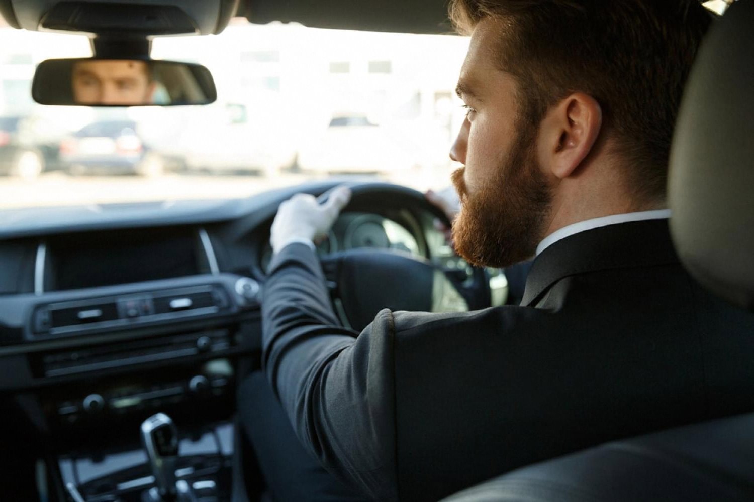 Chauffeur in a suit and white gloves driving a luxury car in Dubai traffic